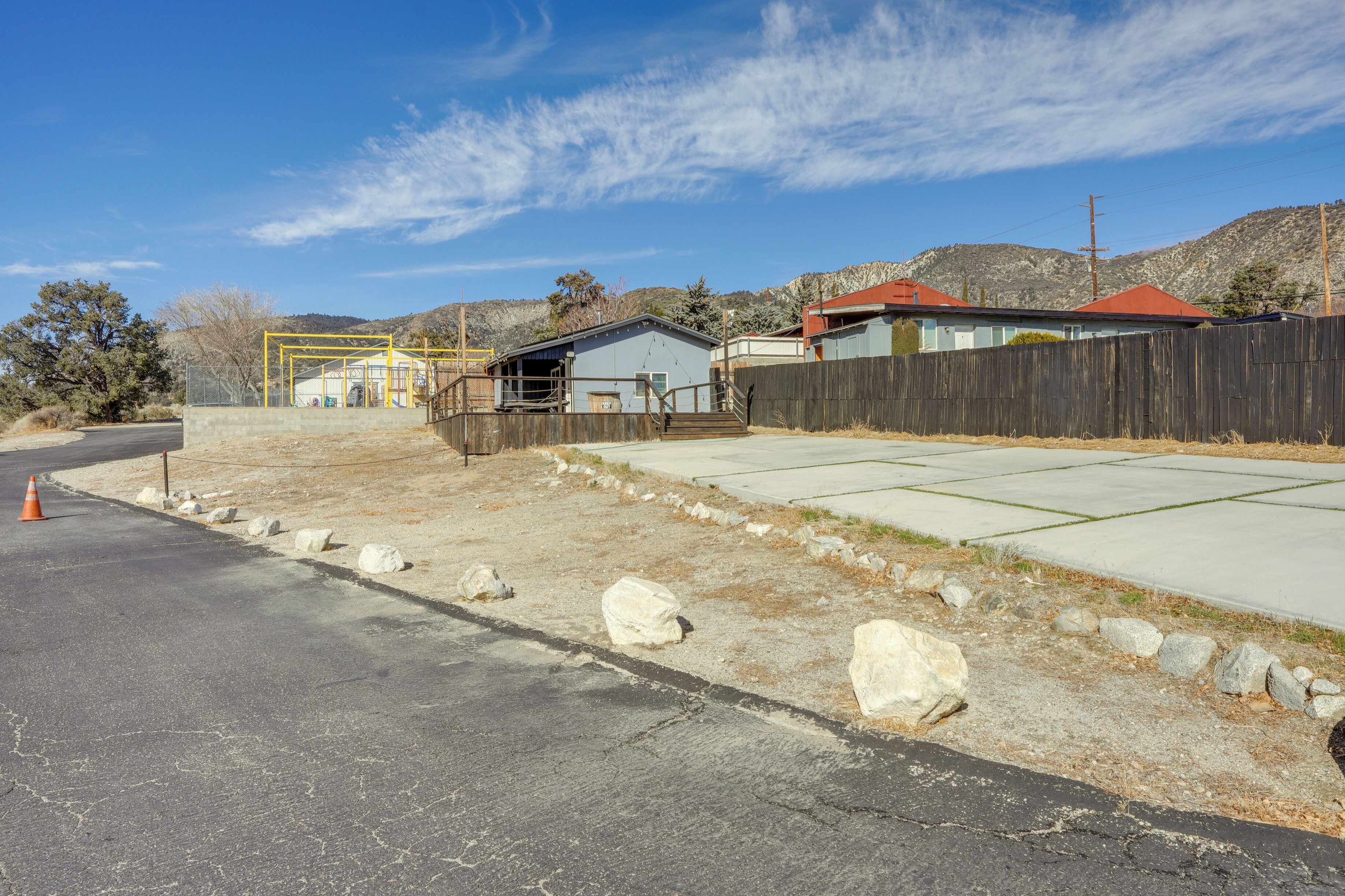 A rural property with a fenced yard, a small building with a red roof, and a clear blue sky.