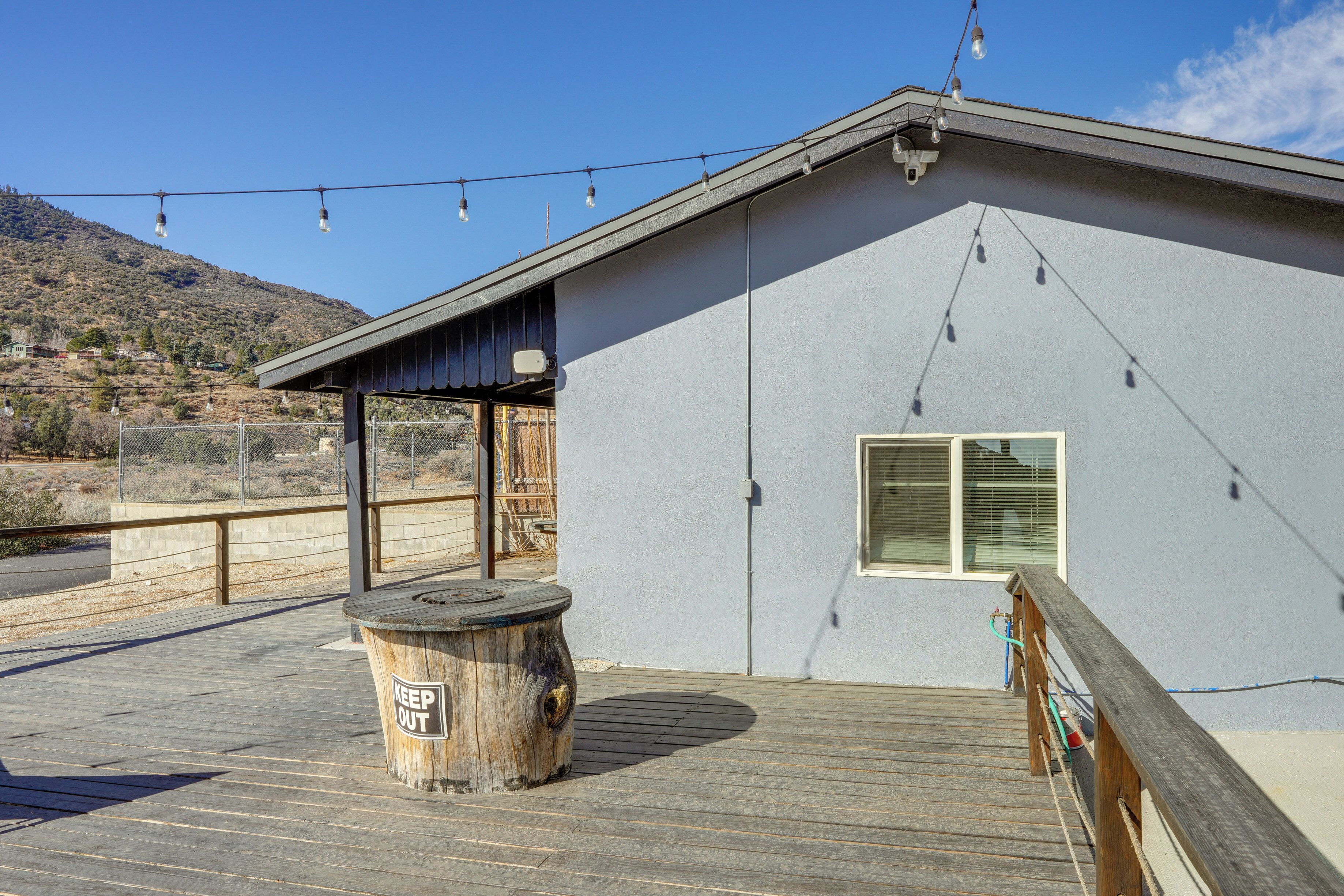 A building with a wooden deck, a 'KEEP OUT' sign, and a mountain in the background.