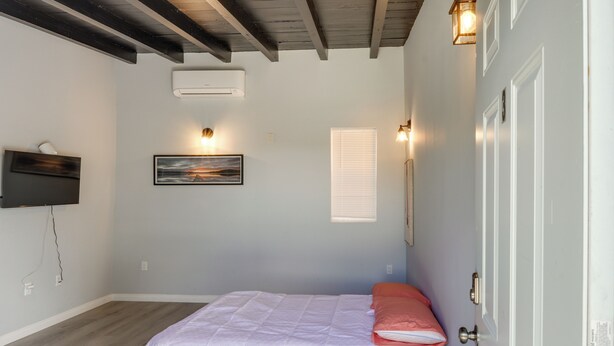 A bedroom with a bed, a painting, an air conditioner, and a door. - 6 Mi to Frazier Mountain: Cozy Studio Retreat (Frazier Park)
