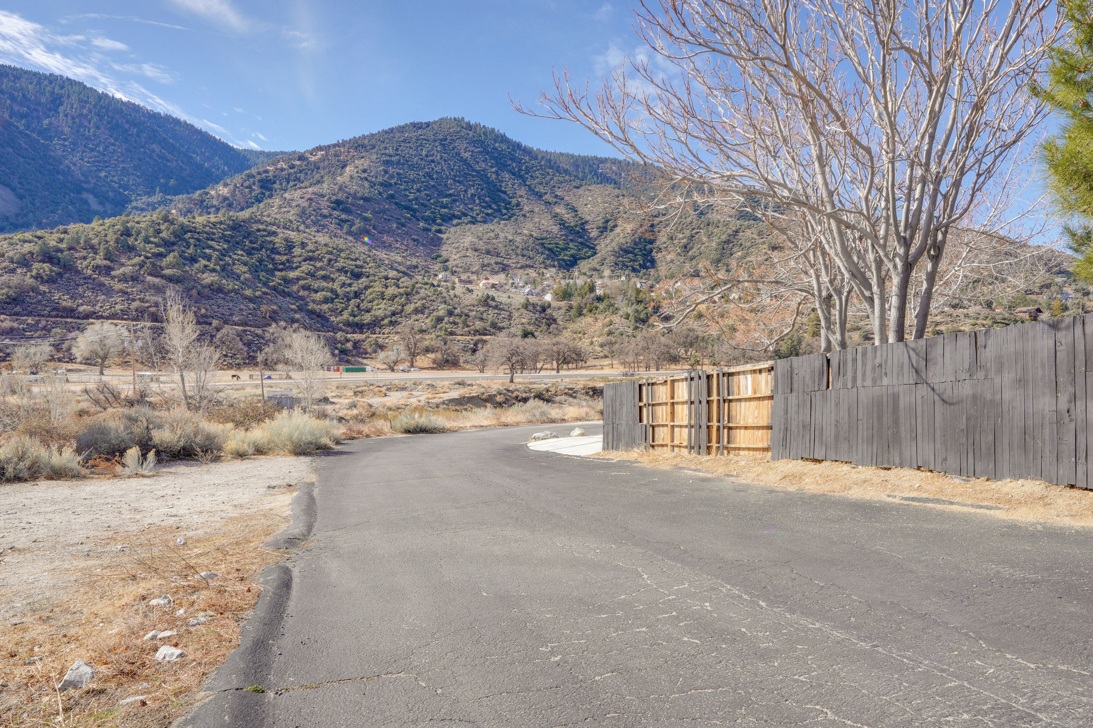 A rural road curving through a mountainous area with a wooden fence on one side.
