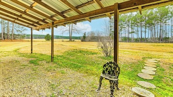 Relax under the shelter, surrounded by a serene grassy field and trees.