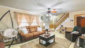 A living room with a brown sofa, a coffee table, a hanging chair, and a staircase leading to a second floor. - 6 Mi to Salisbury: Forest-view Sanctuary! (Parsonsburg)