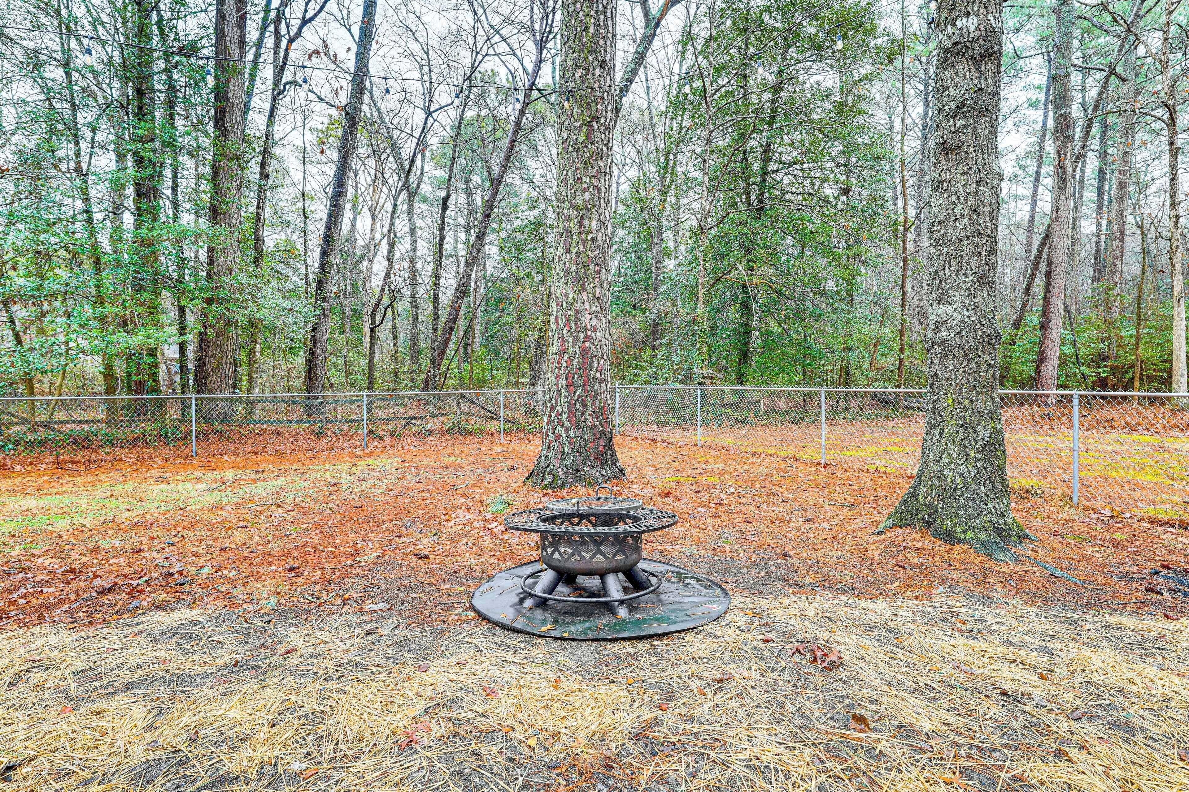 A forested area with a metal fire pit in the center surrounded by dry leaves.