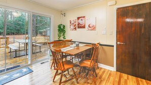 A dining area with a wooden table and chairs, a potted plant, and a door with a wooden panel. - 6 Mi to Salisbury: Forest-view Sanctuary! (Parsonsburg)