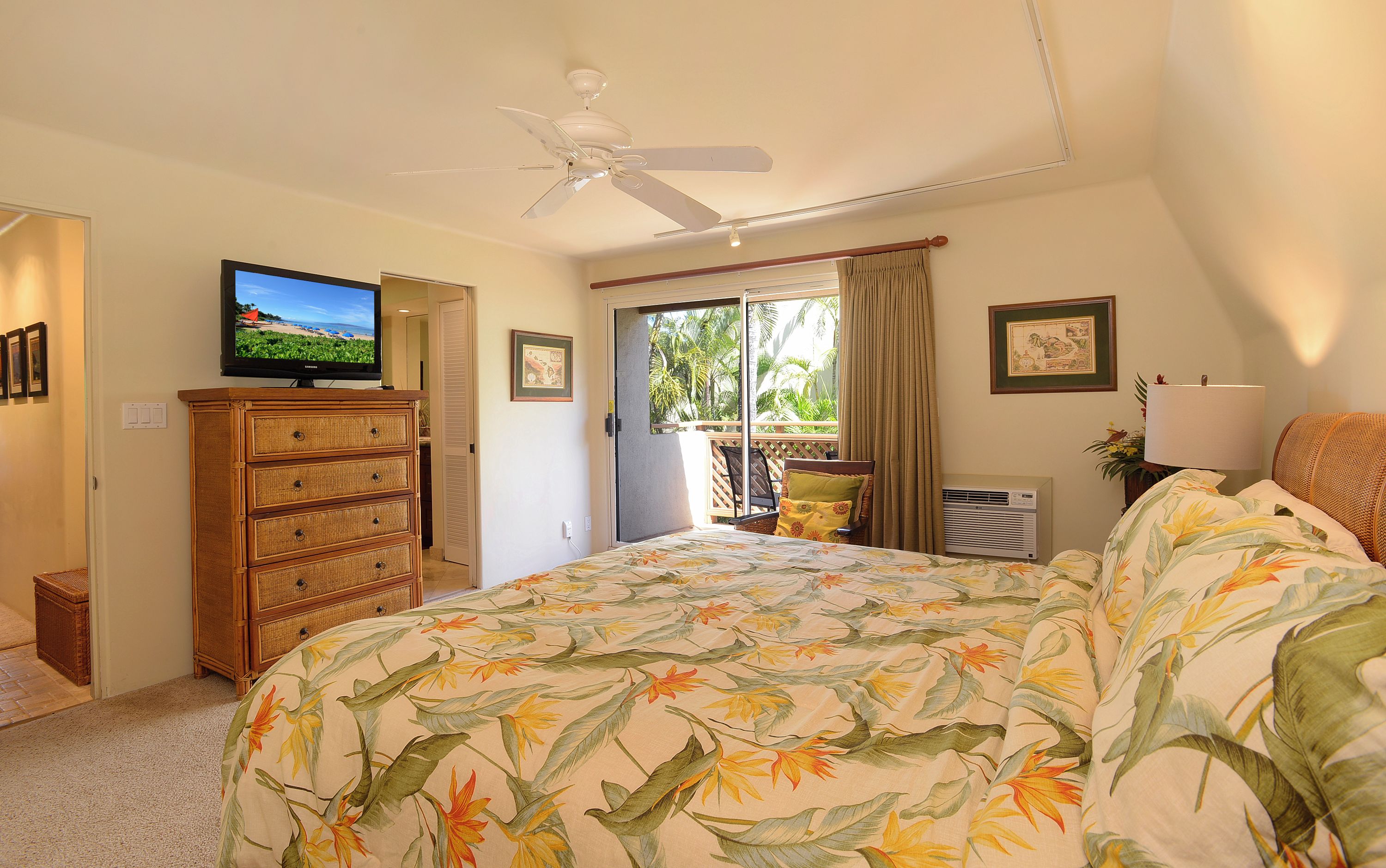 A bedroom with a bed, a dresser, a television, a ceiling fan, and a window with curtains.