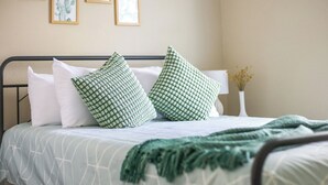 A neatly made bed with a patterned bedspread, two pillows, and a green throw blanket.