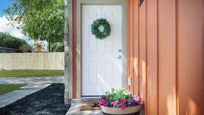 A front door with a wreath, a wooden mailbox, and a flower pot with pink and purple flowers.