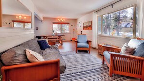 A cozy living room with a wooden sofa, a blue armchair, and a dining area with a table and chairs. - Charming Cherokee Cabin Secluded Stay for 6 Just 10 Minutes to Tahoe! (South Lake Tahoe)