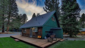 A small, green cabin with a wooden deck, a sliding glass door, and a barbecue area. - Charming Cherokee Cabin Secluded Stay for 6 Just 10 Minutes to Tahoe! (South Lake Tahoe)