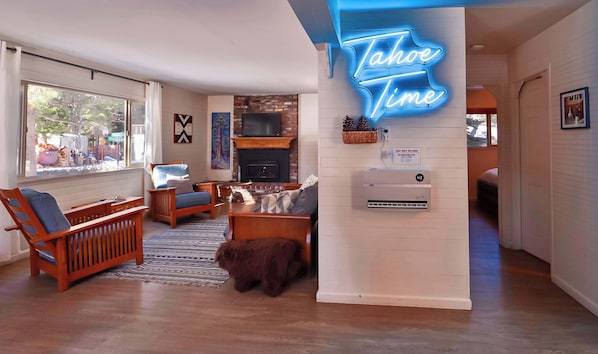 A modern living room with a fireplace, a neon sign, and a space heater. - Charming Cherokee Cabin Secluded Stay for 6 Just 10 Minutes to Tahoe! (South Lake Tahoe)
