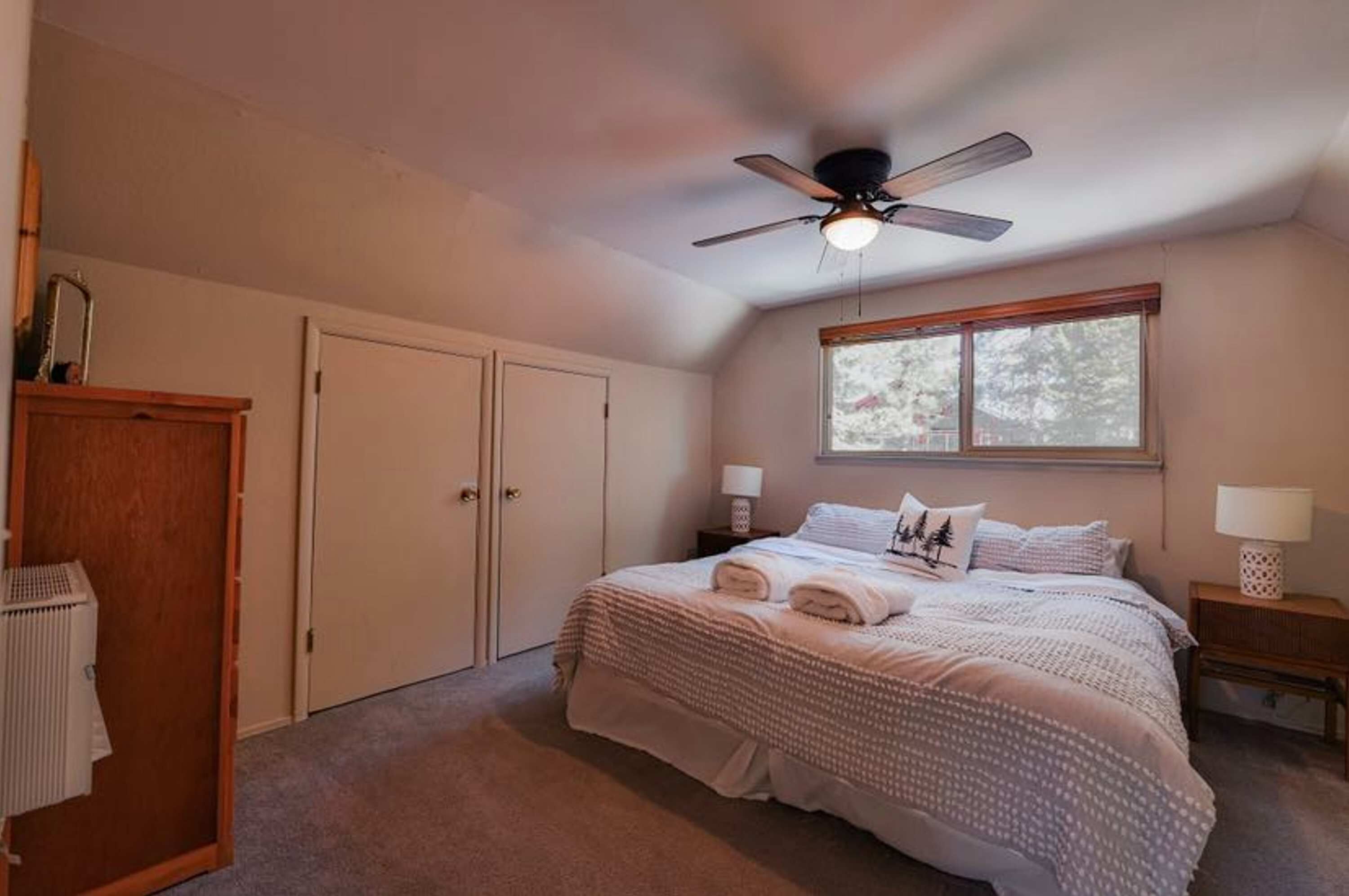 Ein Schlafzimmer mit Bett, Deckenventilator, Fenster und Kleiderschrank.