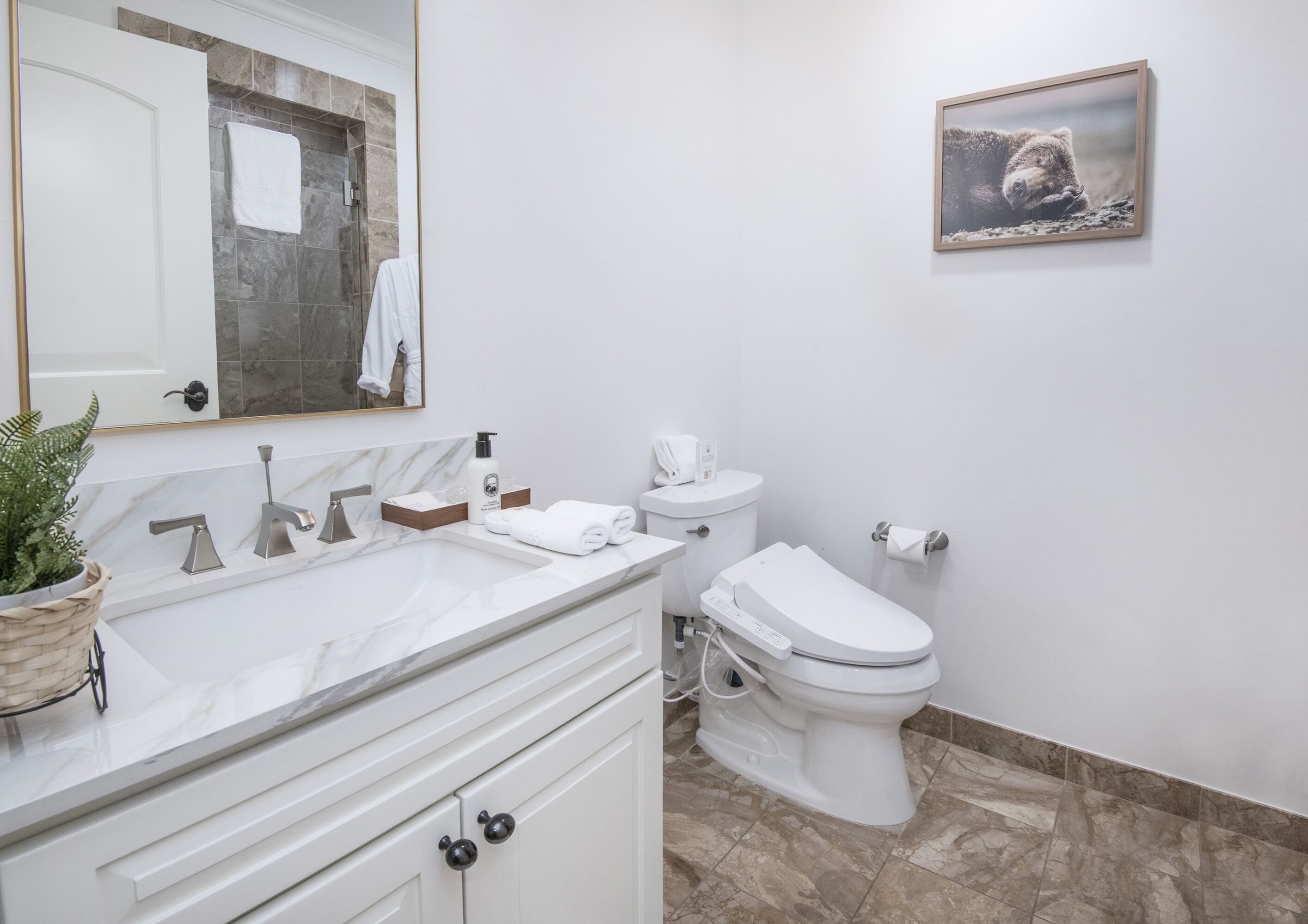 Une salle de bain moderne avec un lavabo en marbre, des toilettes et un tableau encadré au mur.