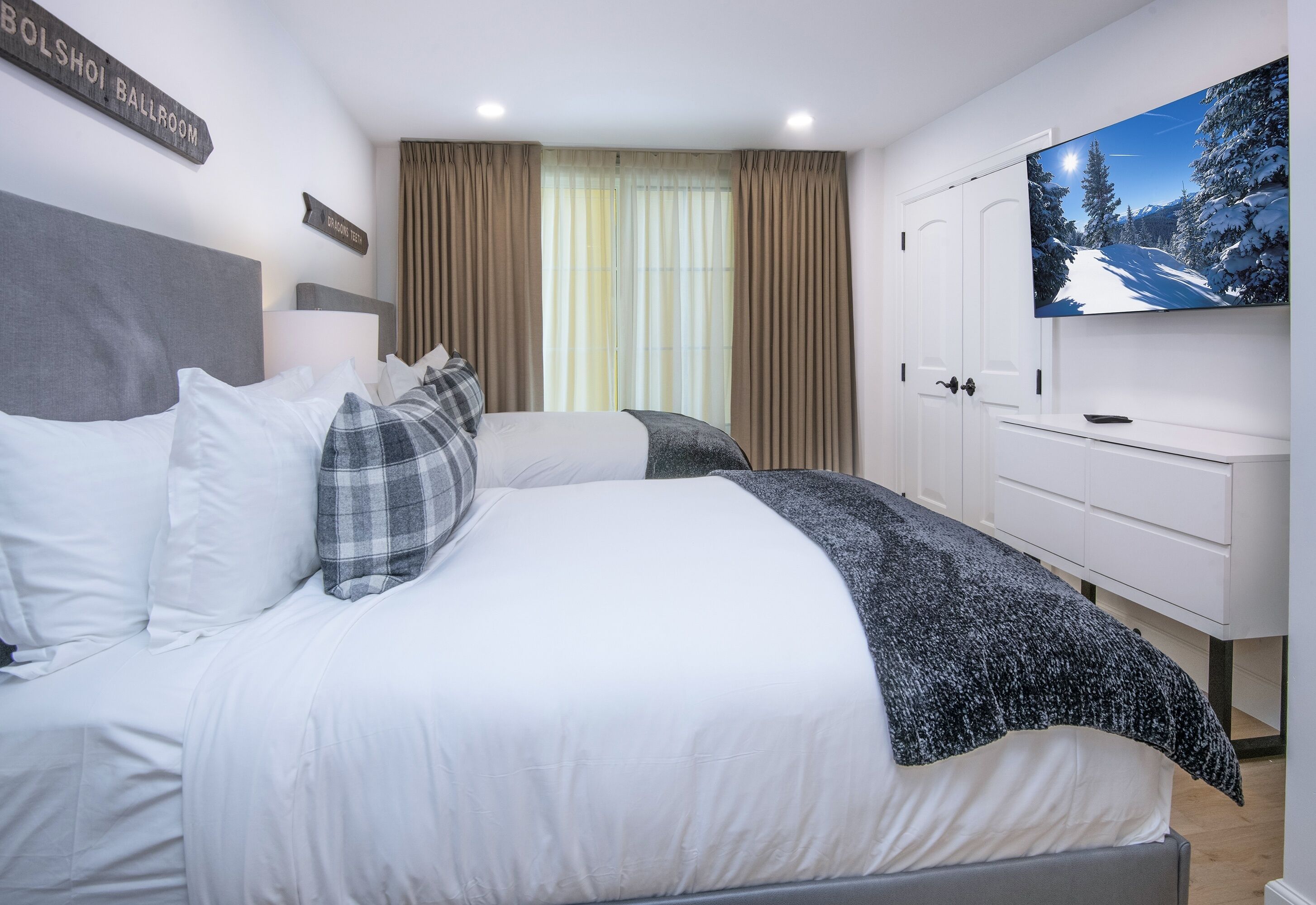 Ein Schlafzimmer mit Bett, Fernseher und einem Fenster mit Vorhängen.
