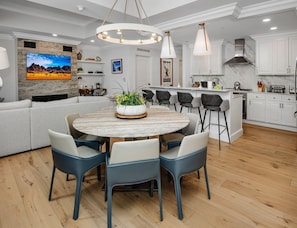 A modern kitchen with white cabinets, a central island, and a dining area with a round table and chairs. - Ritz Carlton Vail #314 3 Bedroom Condo (Vail)
