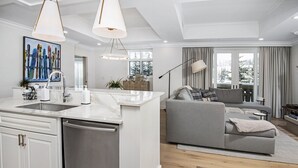 A modern kitchen with a central island, a grey sofa, and a dining area with a lamp. - Ritz Carlton Vail #314 3 Bedroom Condo (Vail)