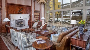 A spacious lobby with a fireplace, comfortable seating, and large windows offering a view of the outside. - Ritz Carlton Vail #314 3 Bedroom Condo (Vail)