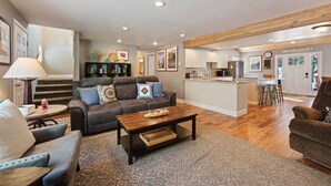 A spacious living room with a dark brown coffee table, a grey sofa with blue cushions, and a patterned rug. - 8 East Butte Ln 3 Bedroom Home (Bend)