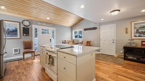 A kitchen with wooden flooring, a central island, a refrigerator, and a clock on the wall. - 8 East Butte Ln 3 Bedroom Home (Bend)