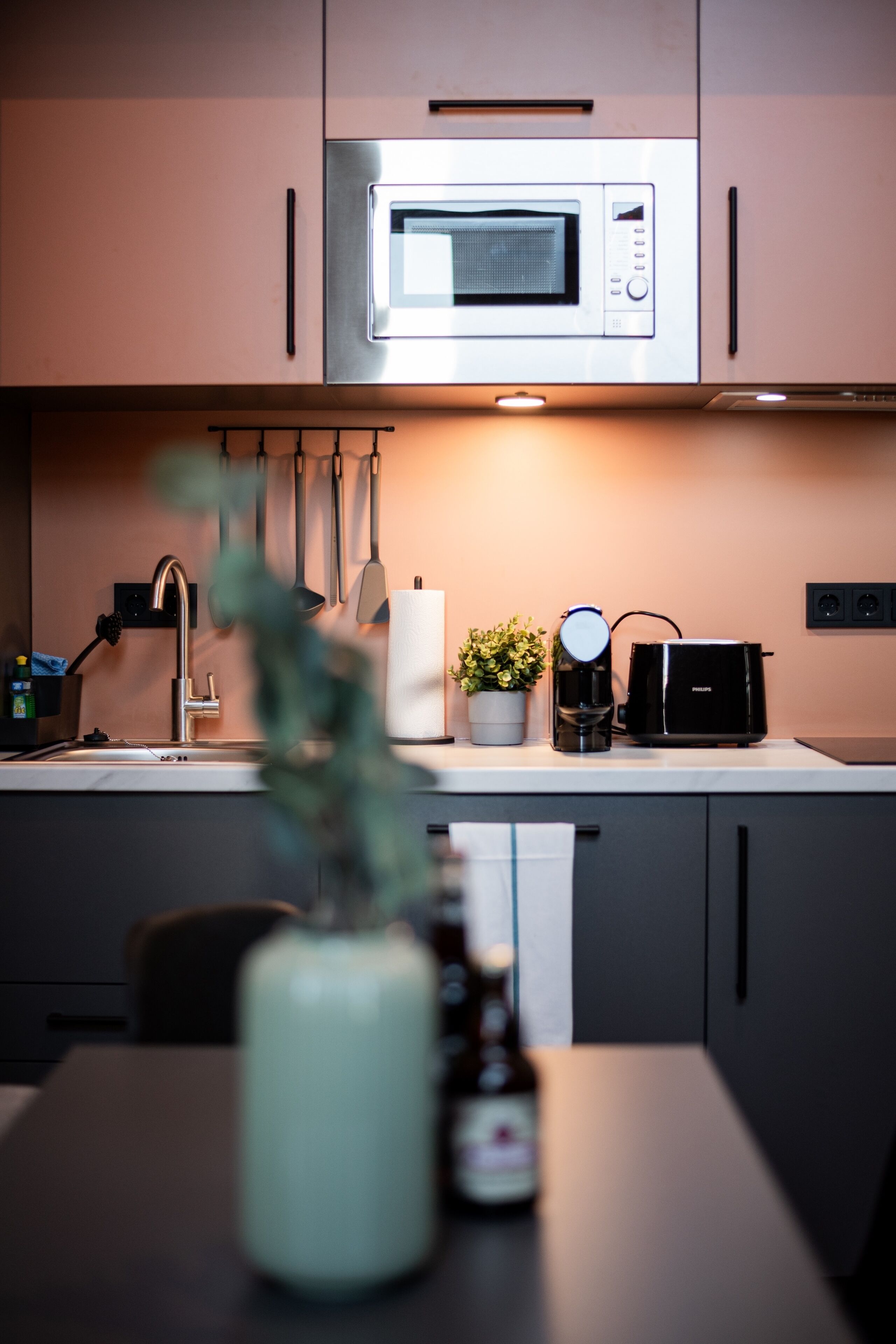 Een moderne keuken met een inbouwmagnetron, koffiezetapparaat en broodrooster.