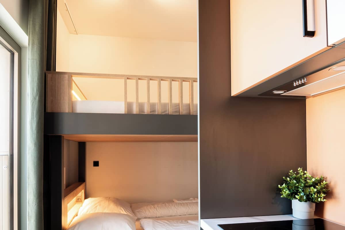 A bunk bed with a kitchen area, including a stove and cabinets.