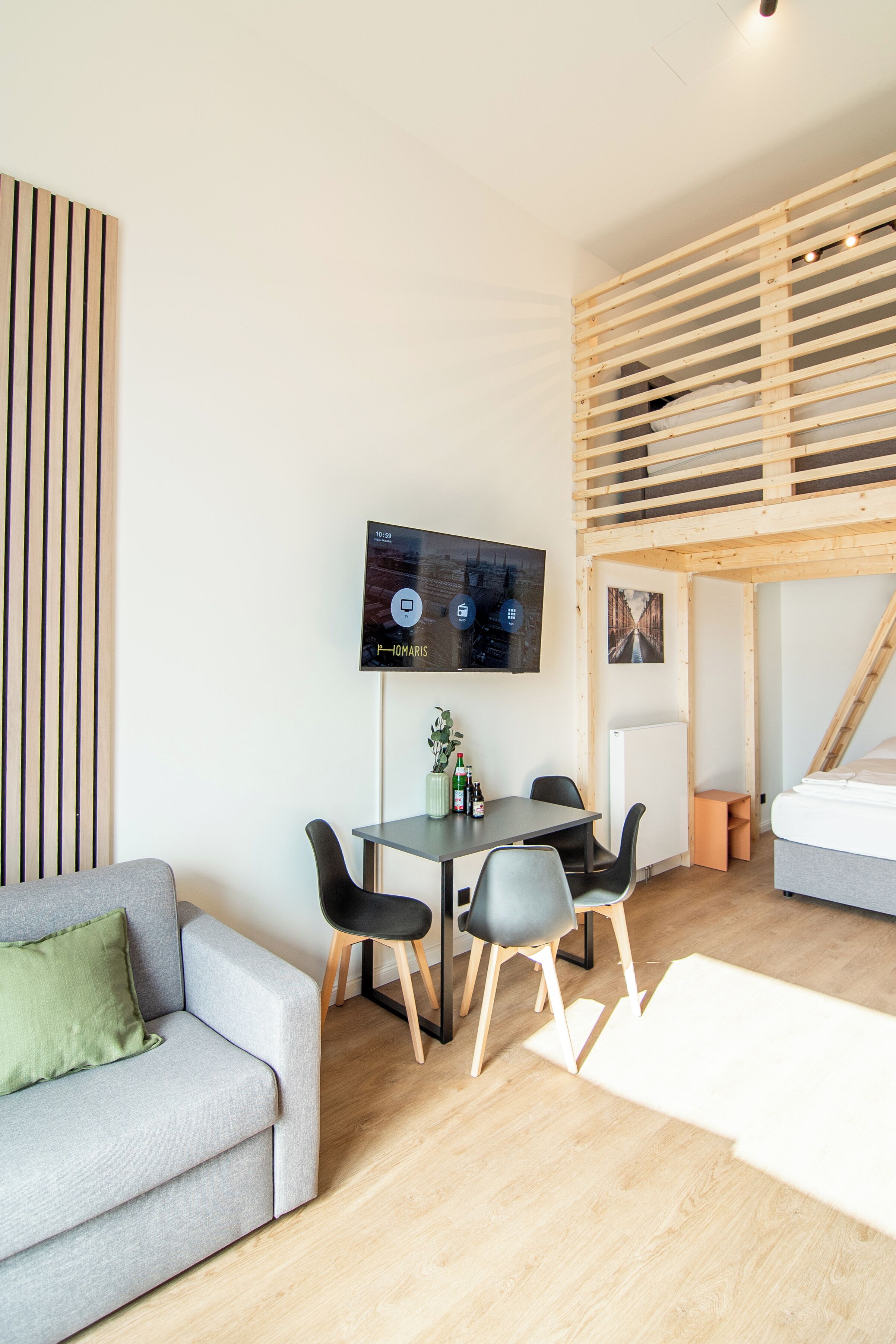 Quarto moderno com teto de ripas de madeira, sofá cinza, mesa de jantar com cadeiras e televisão na parede.