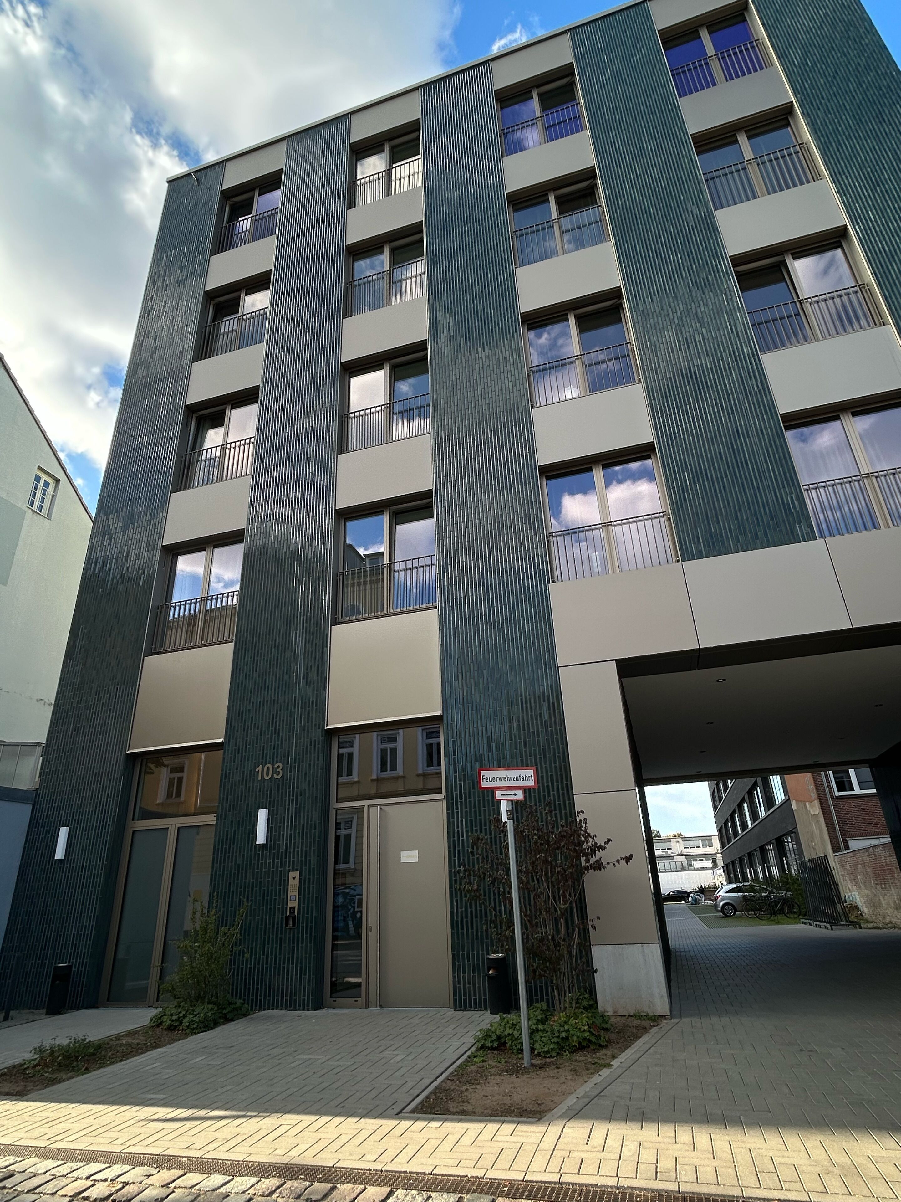 A modern multi-story building with a prominent entrance and a sign indicating a fire exit.