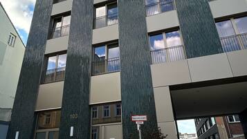 A modern multi-story building with a prominent entrance and a sign indicating a fire exit.