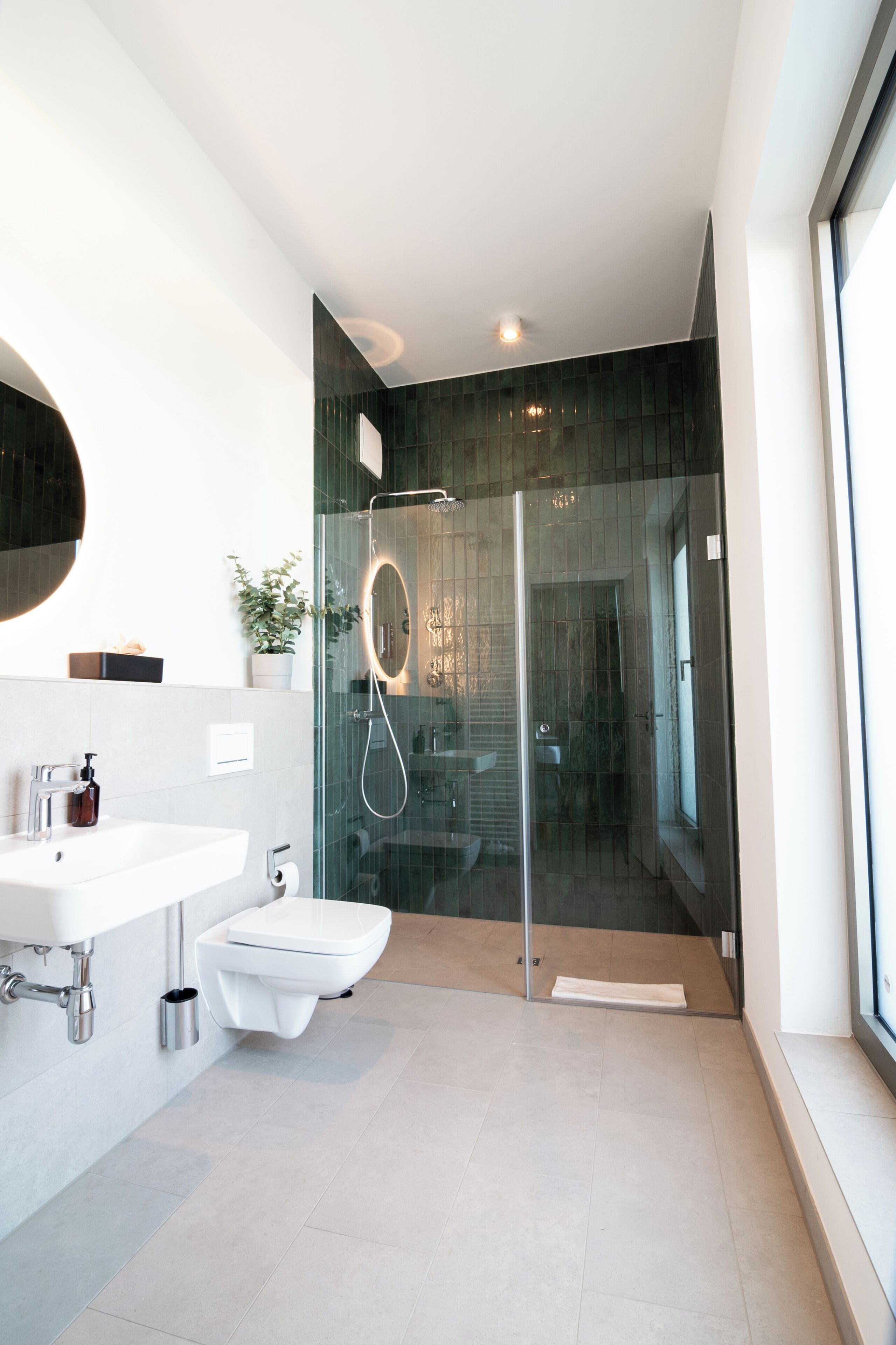 Une salle de bain moderne avec une douche à parois de verre, un lavabo blanc et des toilettes.