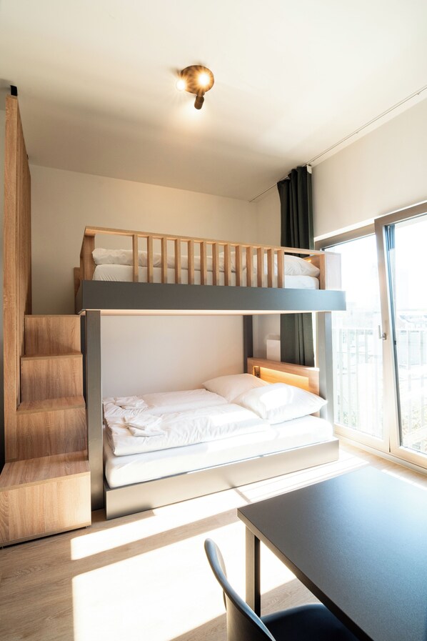 Una habitación moderna con literas, una escalera de madera y una mesa.