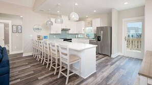 A modern kitchen with a central island, white cabinetry, stainless steel appliances, and pendant lighting. - Perfectly Happy 4 Bedroom Home (Port Bolivar)