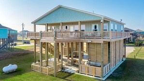 A two-story wooden house with a balcony, a covered porch, and a small deck area. - Perfectly Happy 4 Bedroom Home (Port Bolivar)