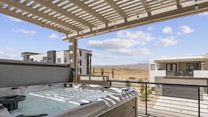 A hot tub on a balcony with a view of modern buildings and a desert landscape. - Beech Bungalow 5 Bedroom Townhouse (St. George)