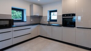 A modern kitchen with white cabinets, black countertops, and a built-in microwave. - Welcome to your dream vacation home! (Eldetal)