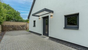 A modern building with a paved driveway, a stone wall, and a large window. - Welcome to your dream vacation home! (Eldetal)
