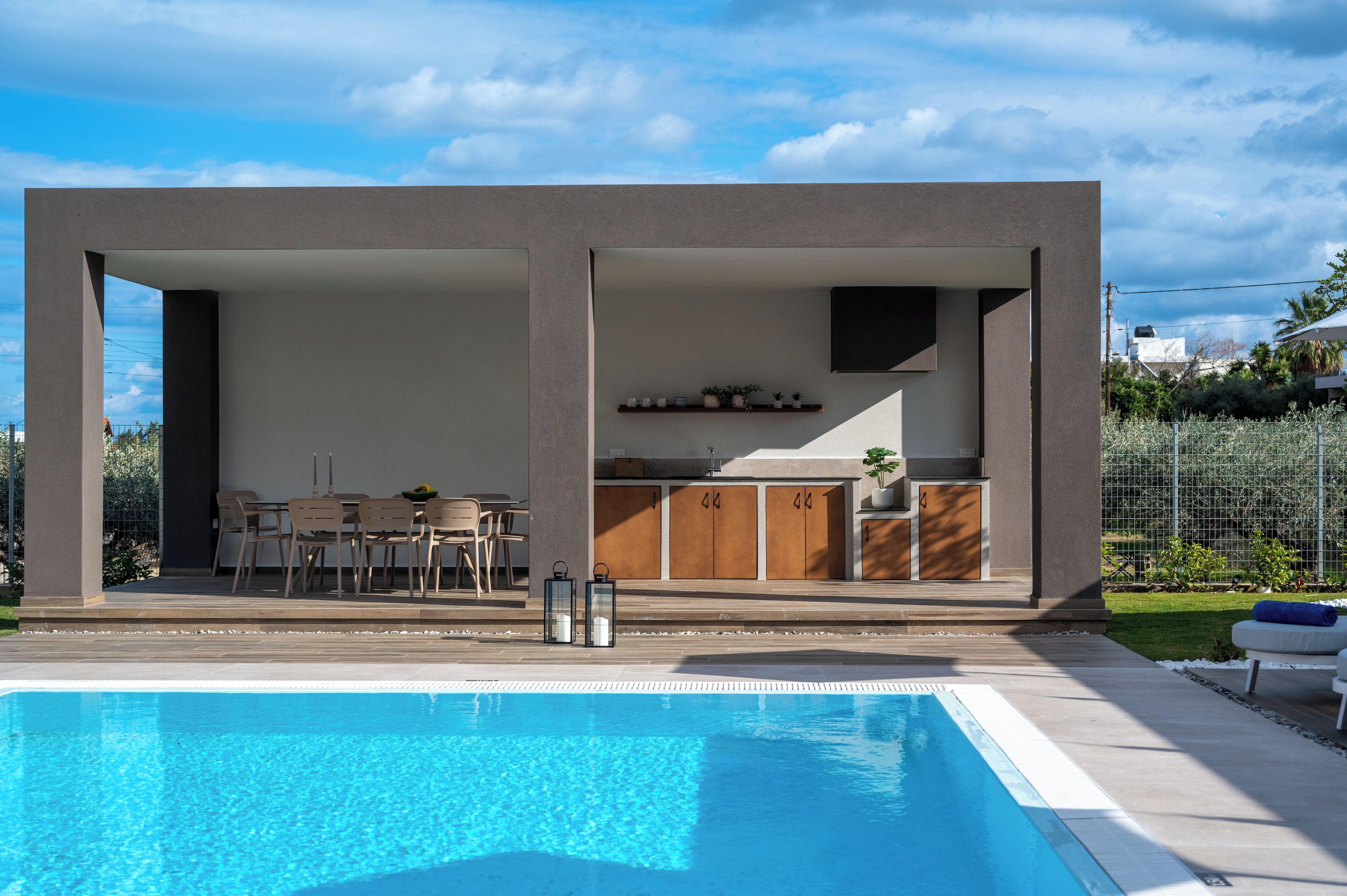 A modern outdoor pool area with a built-in kitchen and seating area.