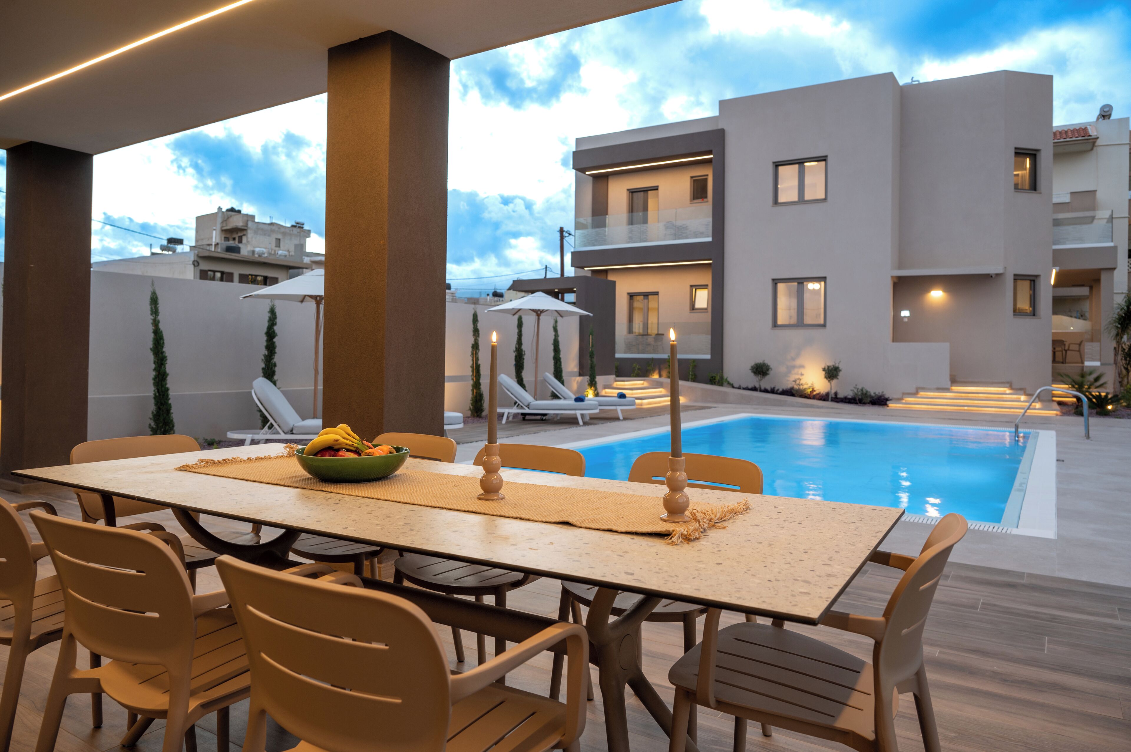 Un espace repas aménagé au bord de la piscine, avec une table, des chaises et des bougies.