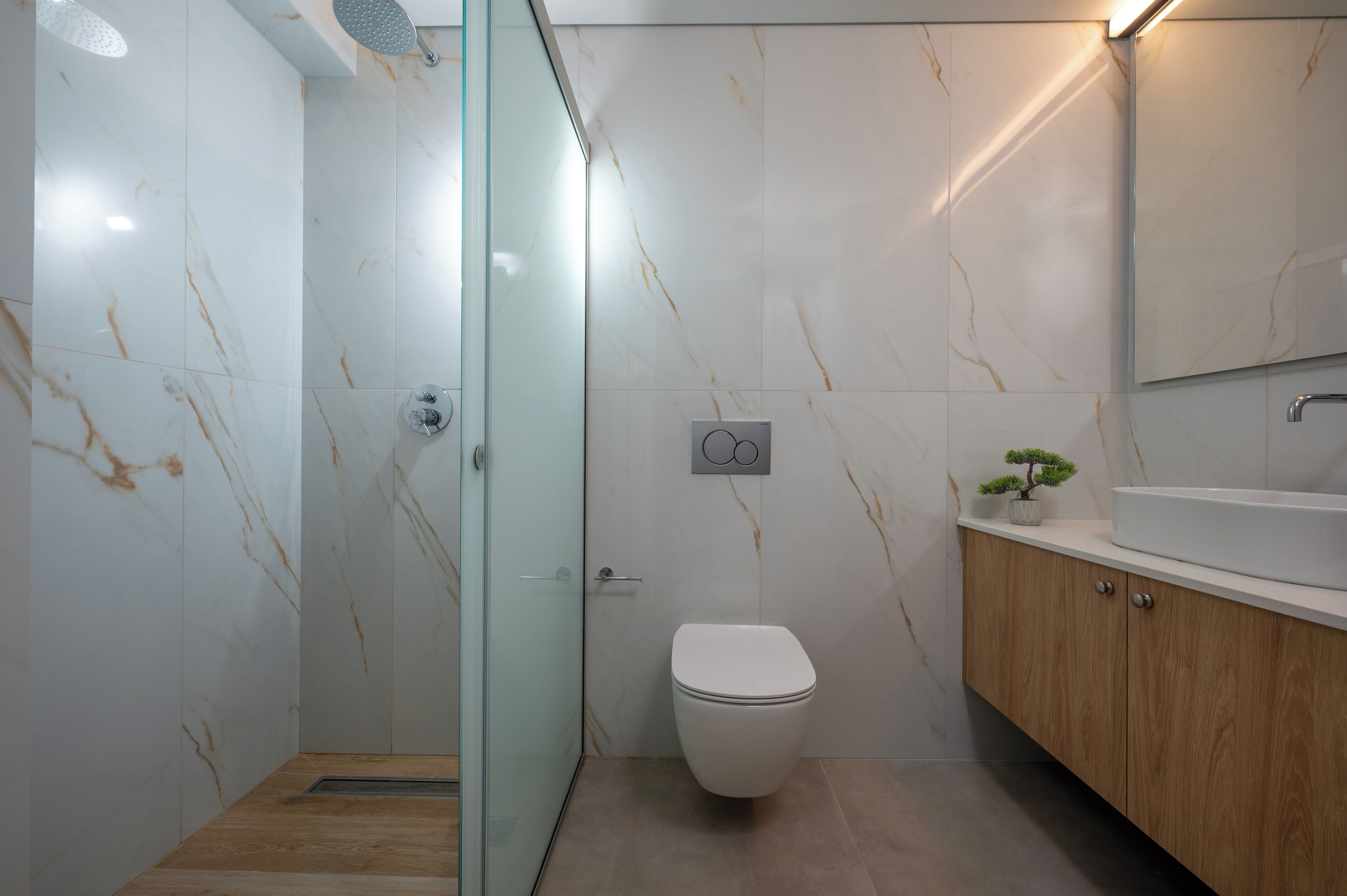 Ein modernes Badezimmer mit einer Duschkabine, einer Toilette und einem Holzlagerflanschrank mit Waschbecken.
