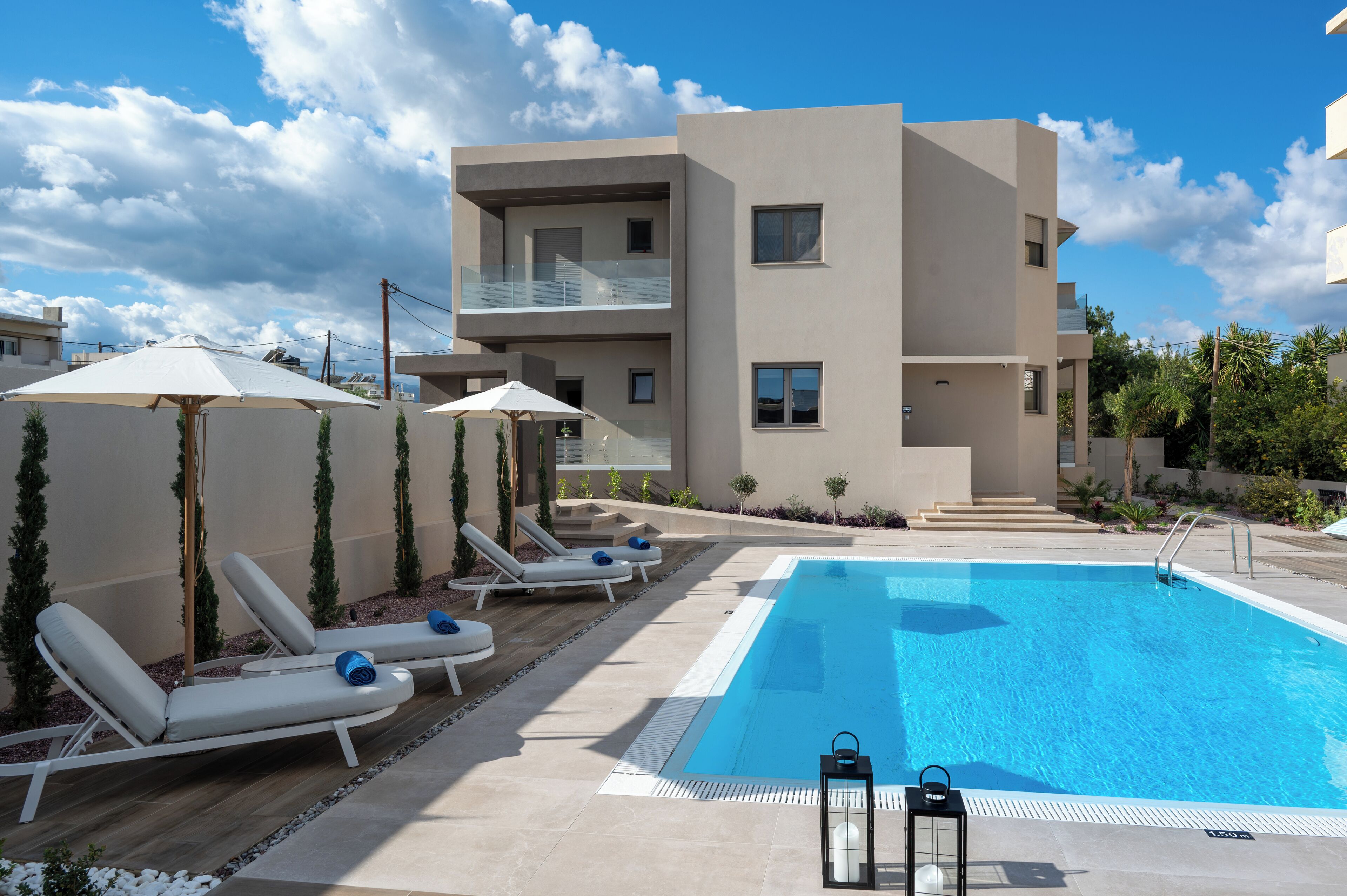 Un edificio moderno con piscina, tumbonas y sombrillas.