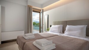 A hotel room with two beds, a large window with curtains, a bedside table, and a view of greenery outside. - Magian Luxury Apartments (Malevizi)