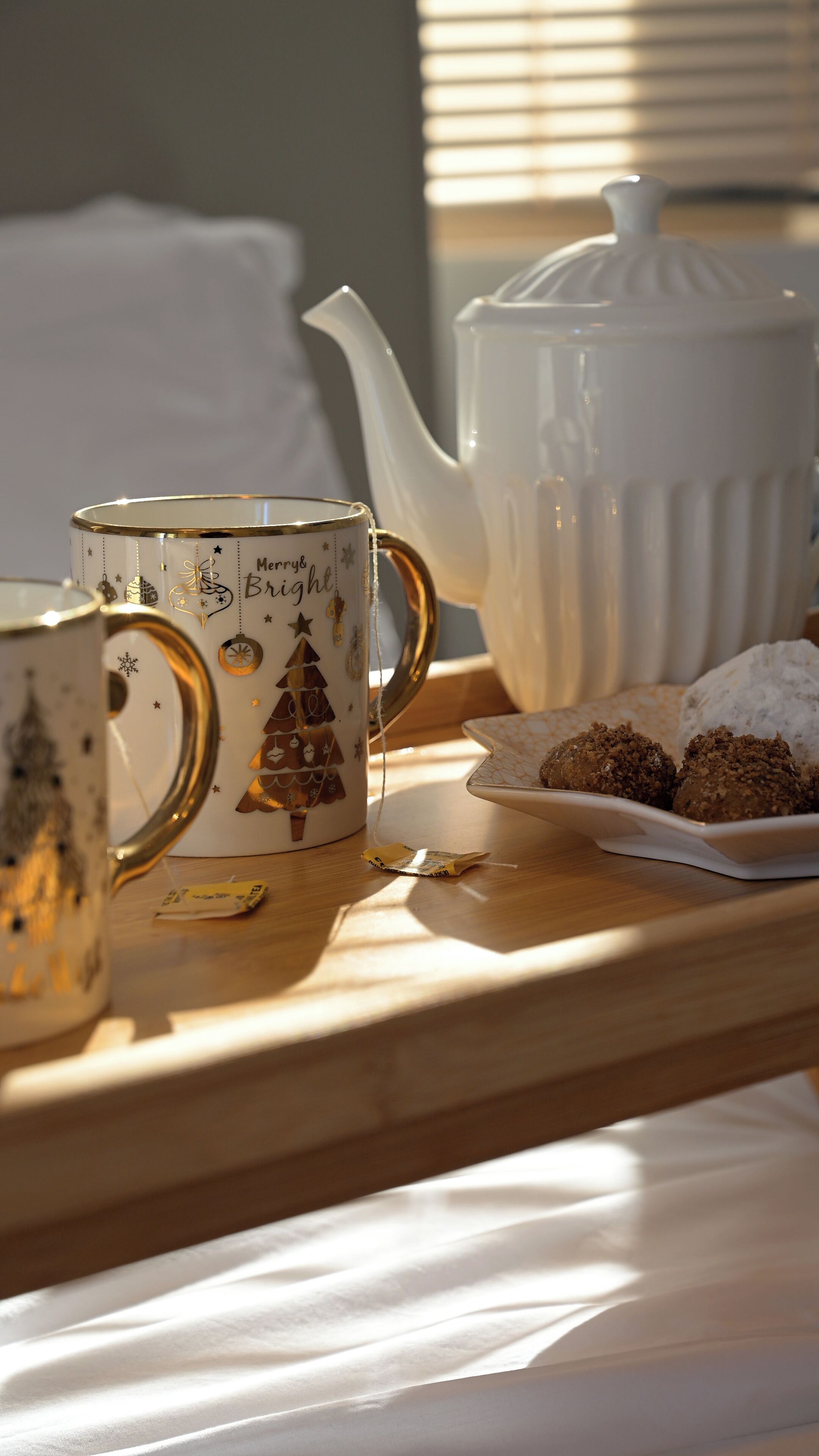 A tray with a mug, teapot, and cookies on a wooden surface.