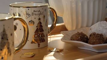 A tray with a mug, teapot, and cookies on a wooden surface.