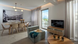 A modern living room with a dining area, a flat-screen TV, and a large window with curtains. - Magian Luxury Apartments (Malevizi)