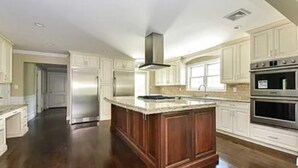 A spacious kitchen with a large island, stainless steel appliances, and wooden cabinets.