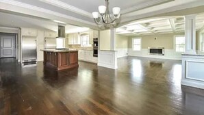 A spacious kitchen with a central island, a large dining area, and a high ceiling with a chandelier.