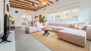 A modern living room with a sectional sofa, a round coffee table, and a large window with blinds.