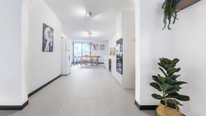 A modern kitchen with white cabinets, a built-in oven, and a dining area with wooden chairs and a table.