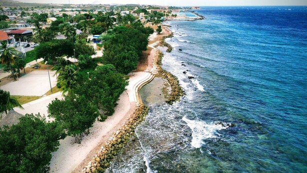 A coastal area with a sandy beach, a rocky shoreline, and a clear view of the ocean.