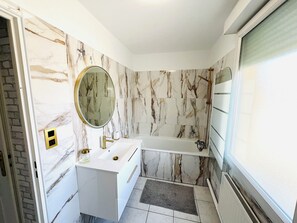 Enjoy a refreshing soak in the bathtub under a large window.