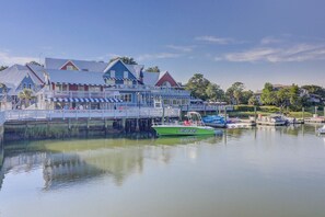 A waterfront property with a dock, a green boat, and a building with a red roof.