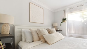 A neatly arranged bedroom with a bed, bedside tables, a hanging plant, and a wall-mounted artwork. - Pets welcome, family friendly home. 5 minute drive to beaches. (Aroona)